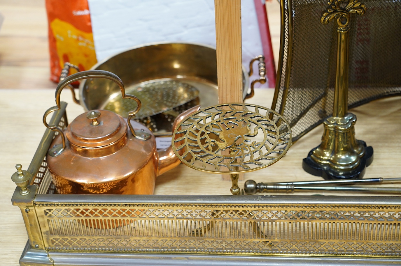 A Victorian brass fender, a fire screen, implements, fire dogs, a bronze pestle and mortar, a copper helmet coal scuttle, etc. Condition - fair